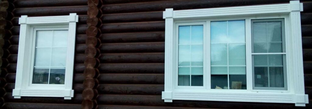 Белые окна с коричневыми наличниками в деревянном доме